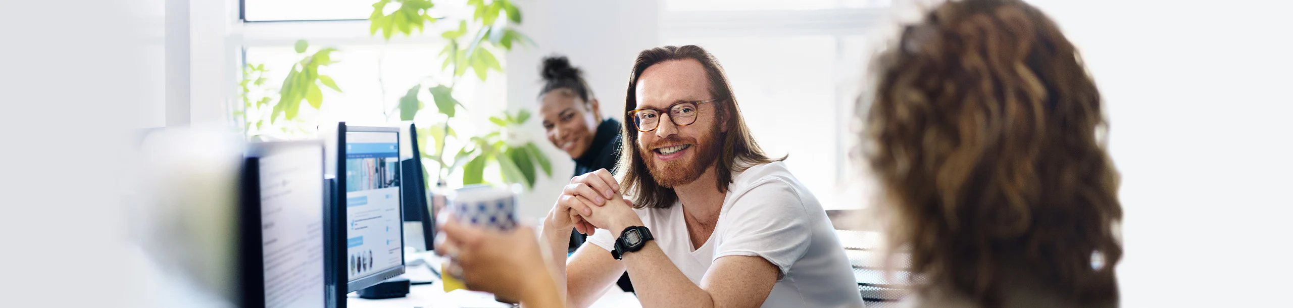 Zwei Frauen und ein Mann sitzen im Büro und unterhalten sich.