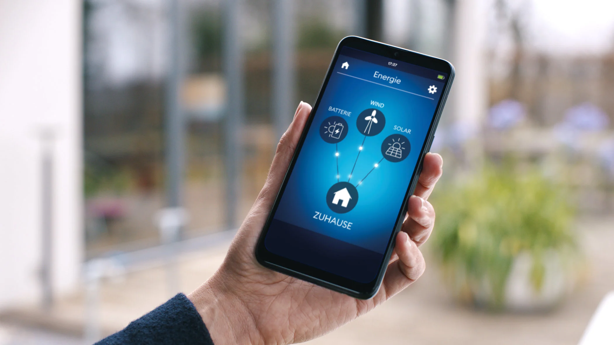 Eine Hand hält ein Smartphone mit einer Smart-Home-App.