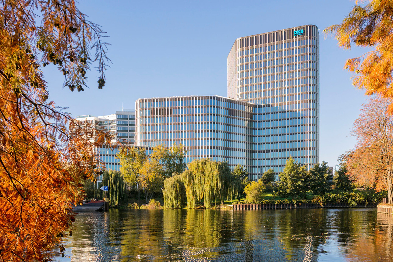 Ein modernes mehrstöckiges Hochhausgebäude mit Wasser und Bäumen im Vordergrund
