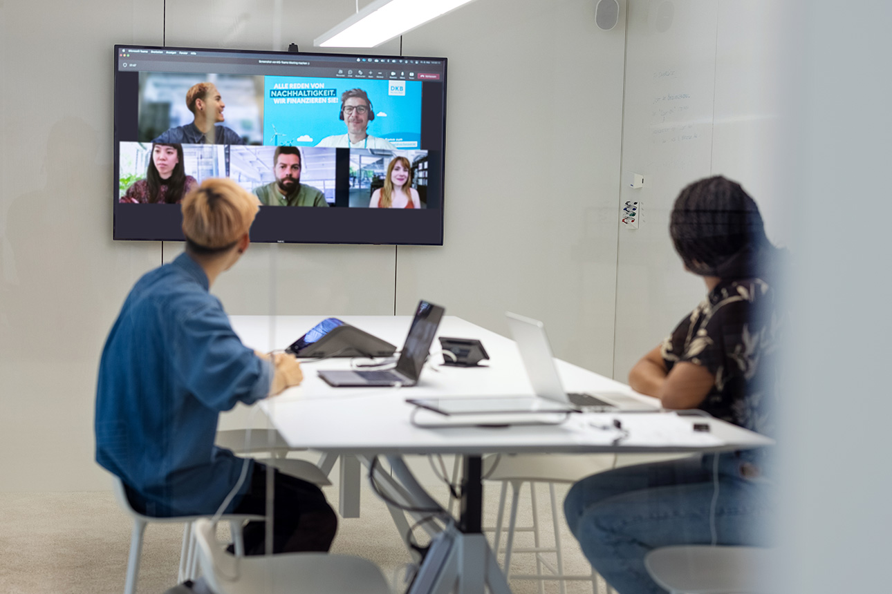 Zwei Personen nehmen an einer Videokonferenz an einem Tisch mit Laptop teil