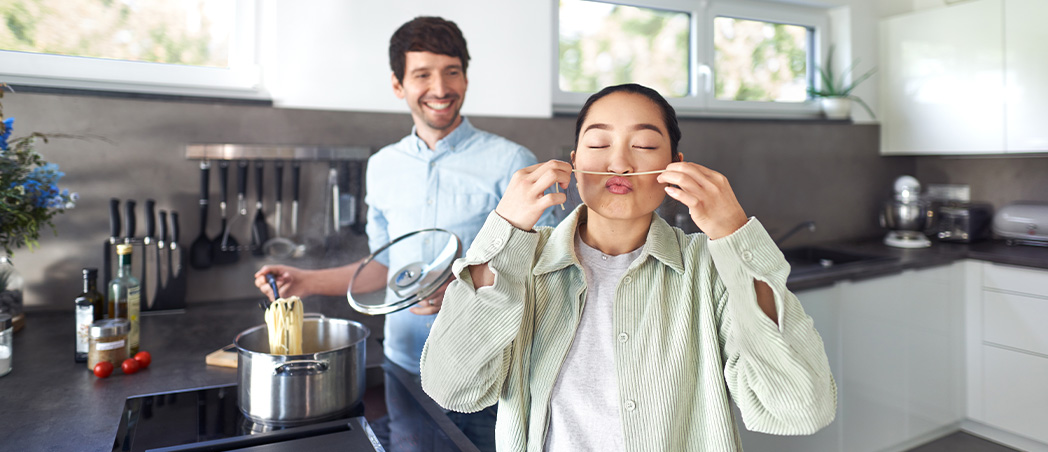 Eine Frau und ein Mann kochen Nudeln