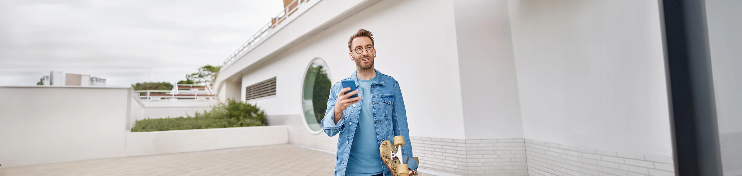 Ein Mann mit Smartphone und Skateboard in der Hand