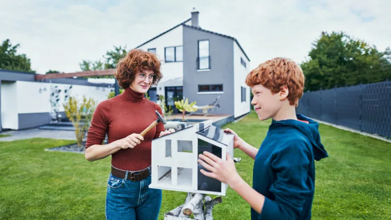 Eine Frau und ein Kind bauen ein Vogelhaus.