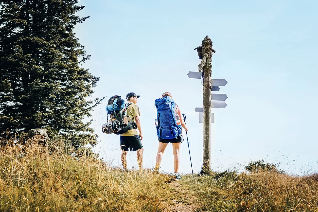 2 Wanderer vor vielen Wegweisern.