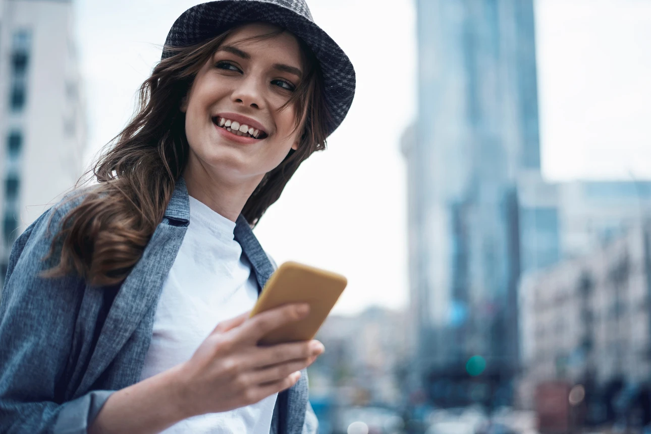 Lächelnde Frau mit Smartphone in moderner Stadt