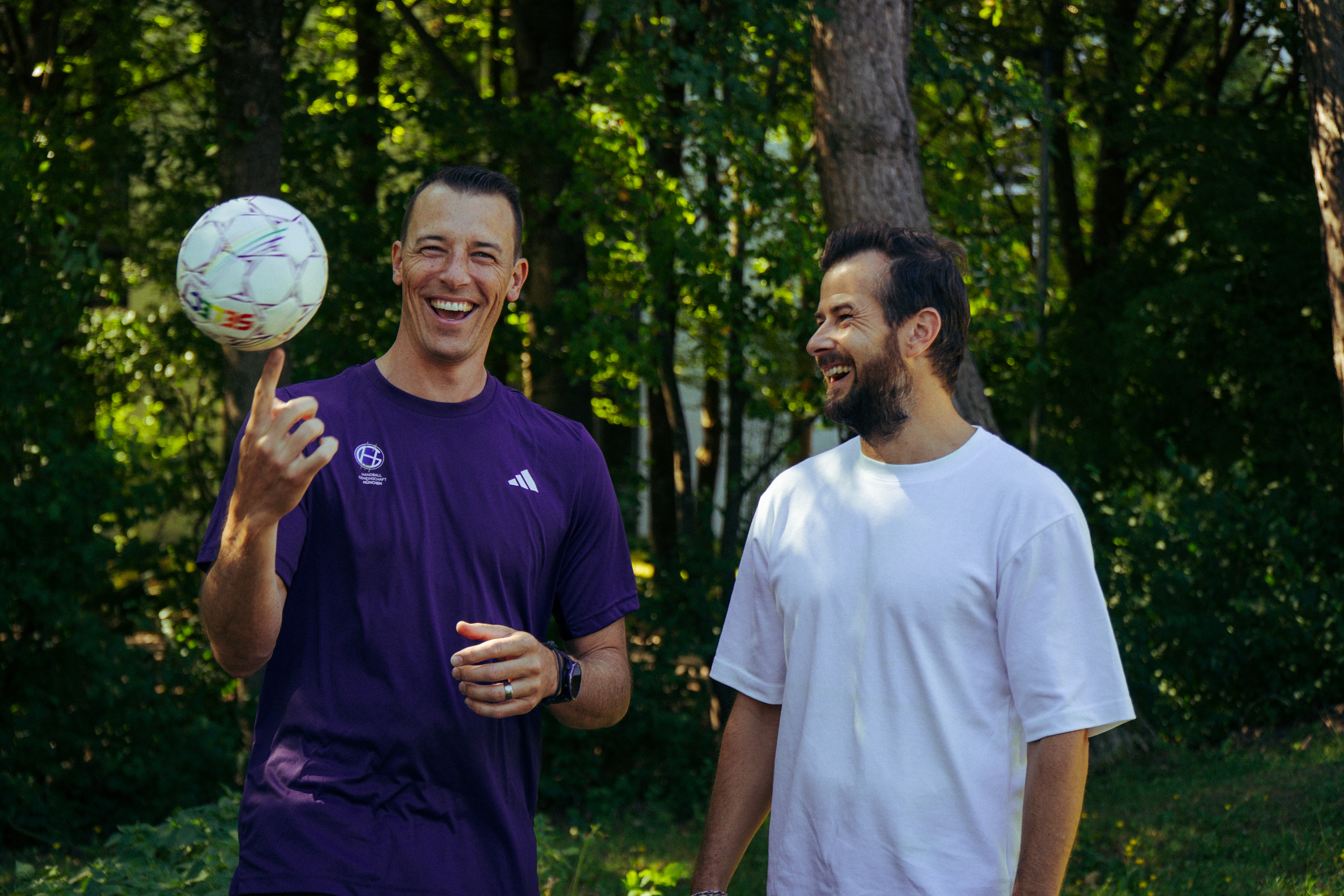 Zwei Männer lachen beim Spaziergang mit Fußball
