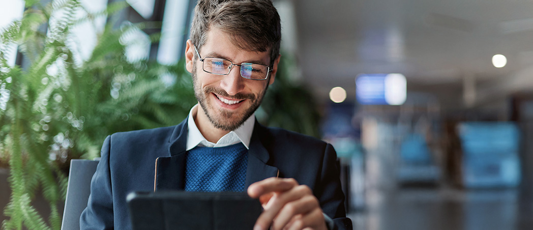 Ein Mann sitzt in einem Stuhl mit einem Tablet in der Hand