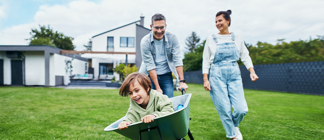 Familie spielt fröhlich im Garten des eigenen Hauses