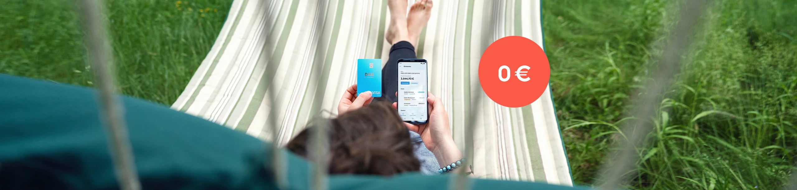 Person in Hängematte hält Visa Debitkarte und nutzt DKB App