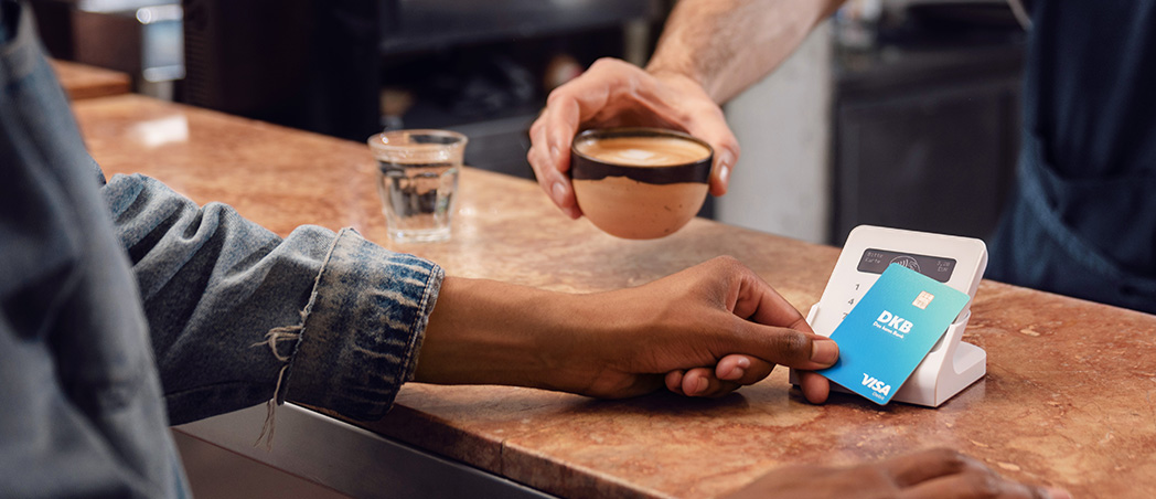 Person bezahlt mit Debitkarte am Kartenterminal im Café