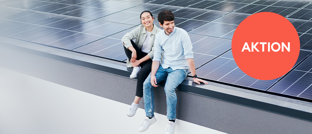 Eine Frau und ein Mann sitzen auf einem Dach mit Solarpanelen