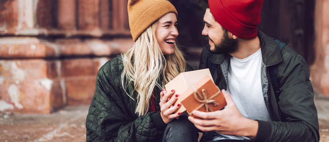 Ein Pärchen lächelt sich an und tauscht Geschenke aus