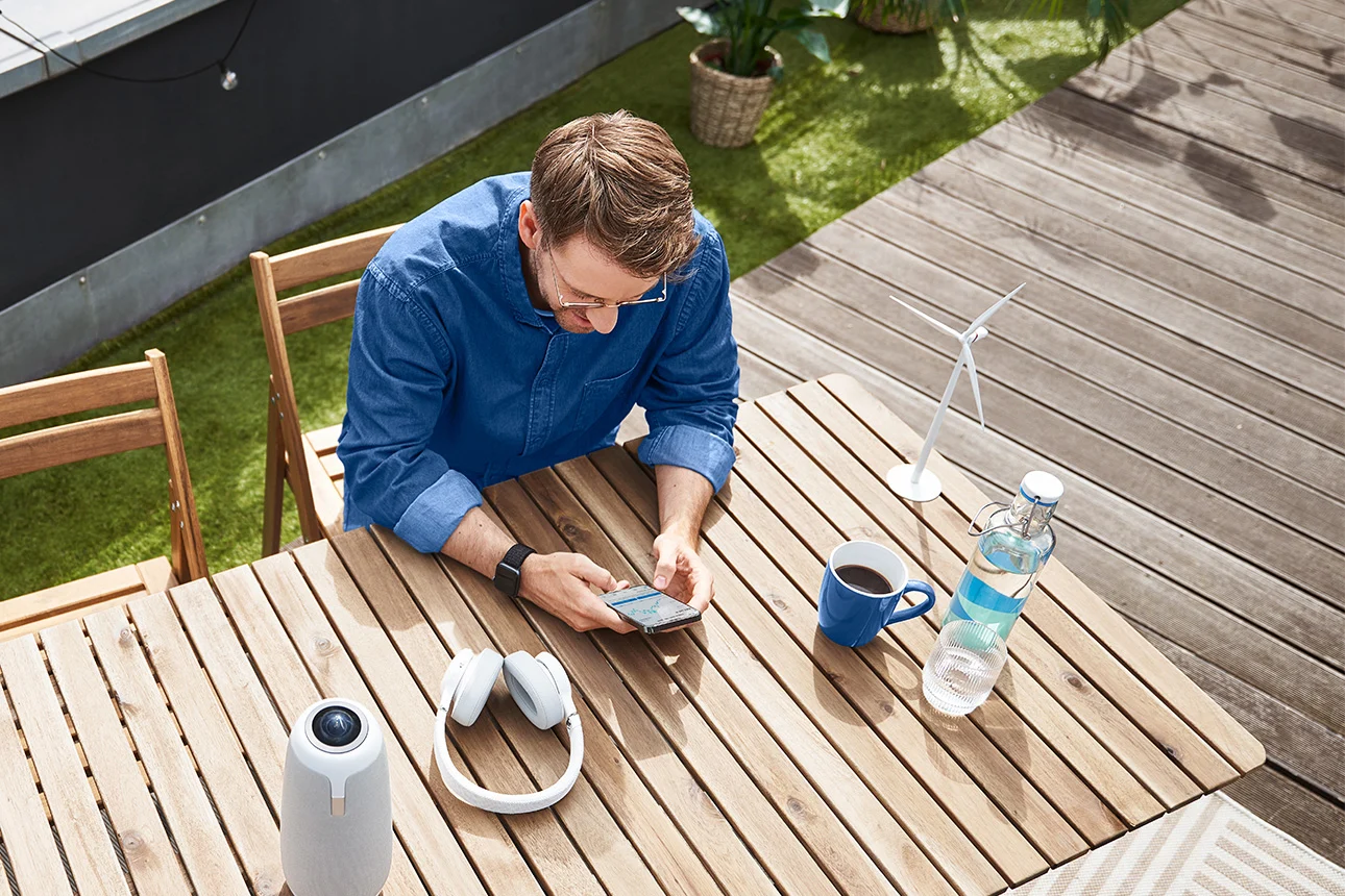 Mann auf Terrasse mit Handy und Kopfhörern