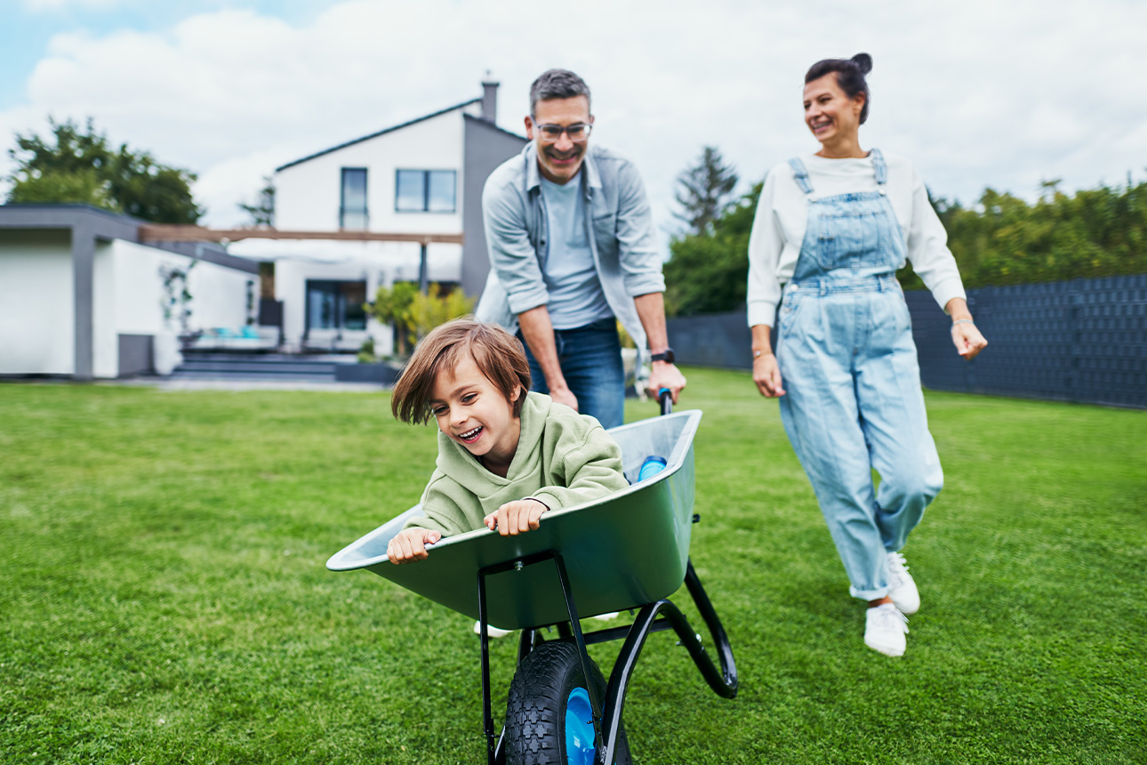 Familie spielt fröhlich im Garten des eigenen Hauses