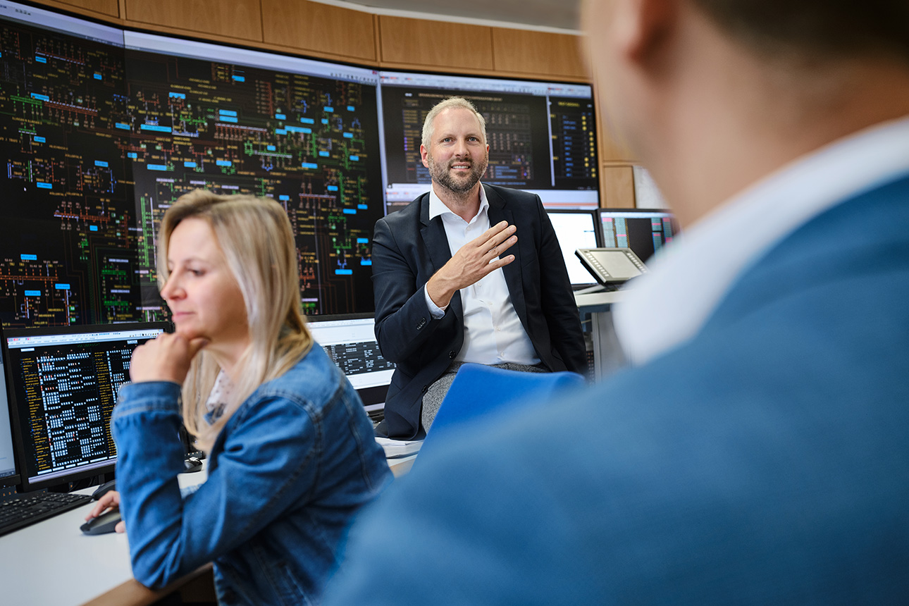 Drei Personen vor den Monitoren einer Netzleitstelle