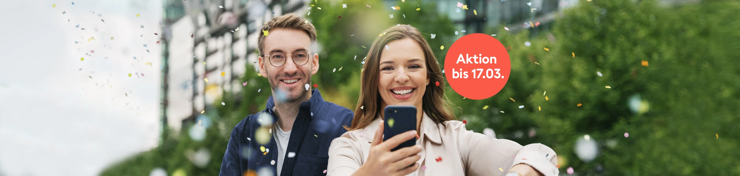 Mann und Frau mit Smartphone im Konfetti-Regen
