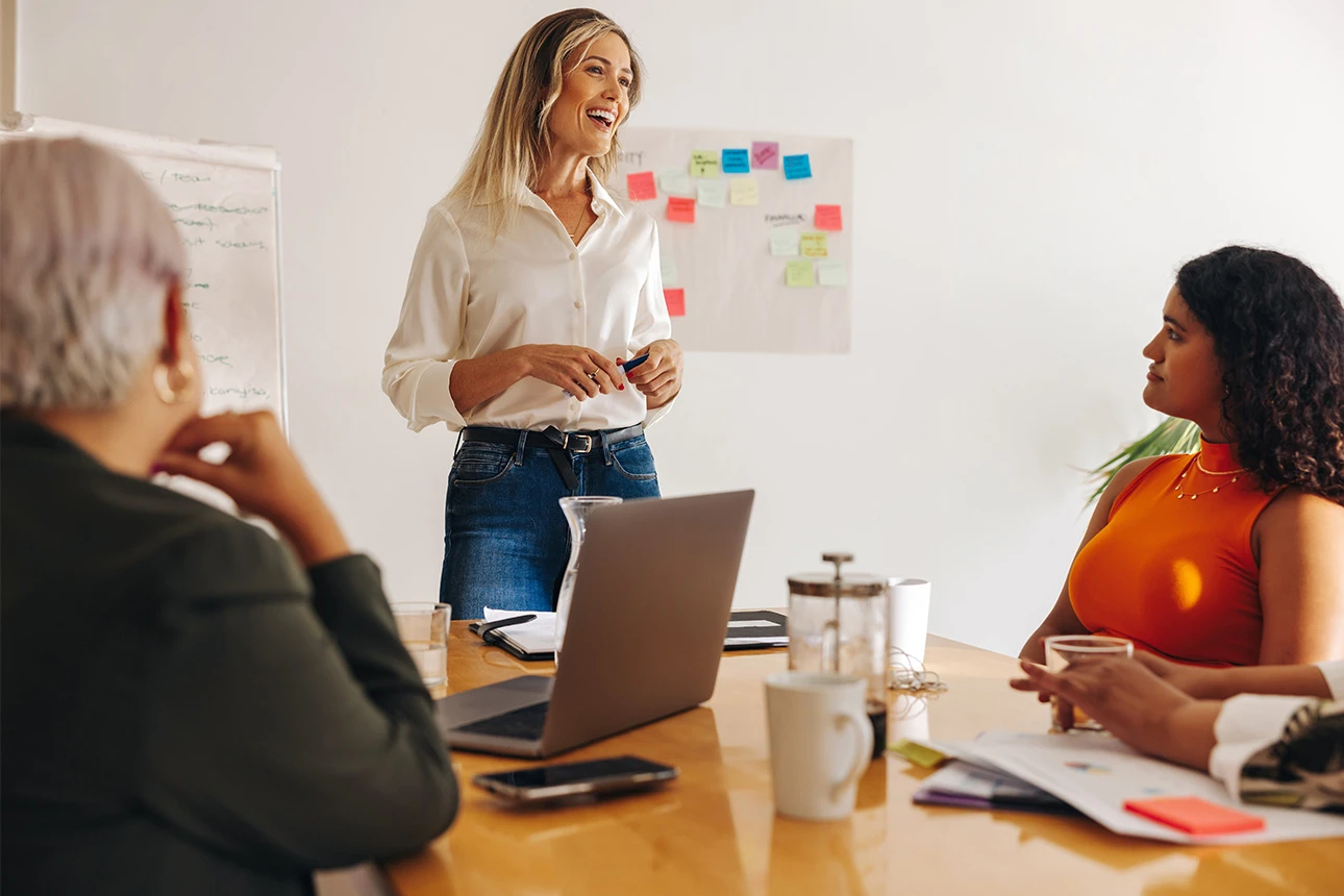 Frau präsentiert Ideen vor Kollegen im Meeting mit Whiteboard