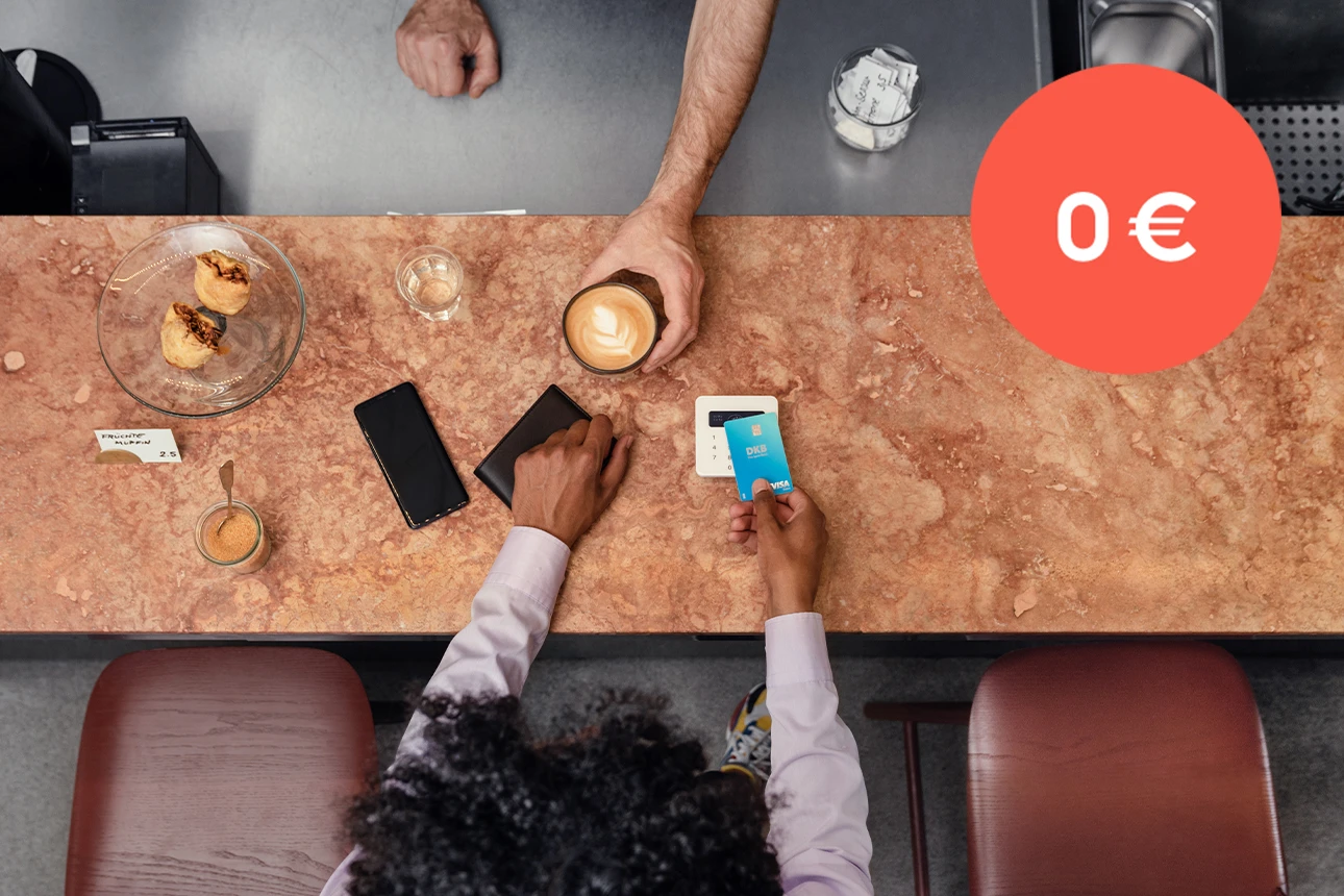 Eine Frau bezahlt ihren Kaffee mit der Visa Debitkarte der DKB