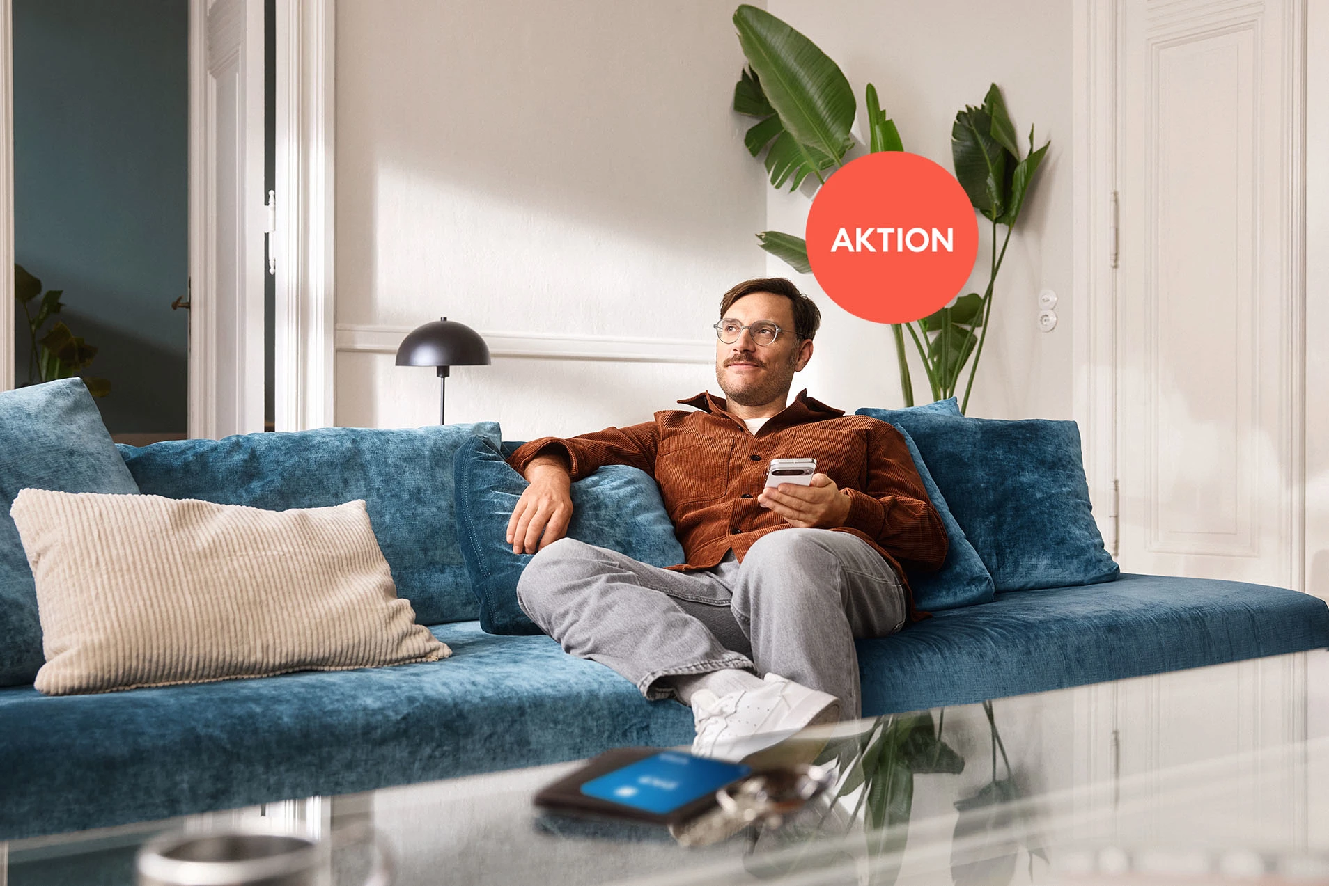Ein Mann mit Smartphone sitzt auf der Couch