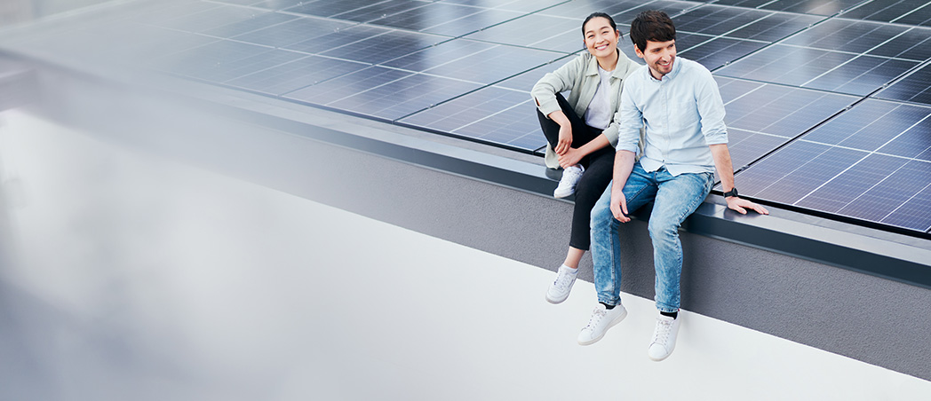Eine Frau und ein Mann sitzen auf einem Dach mit Solarpanelen