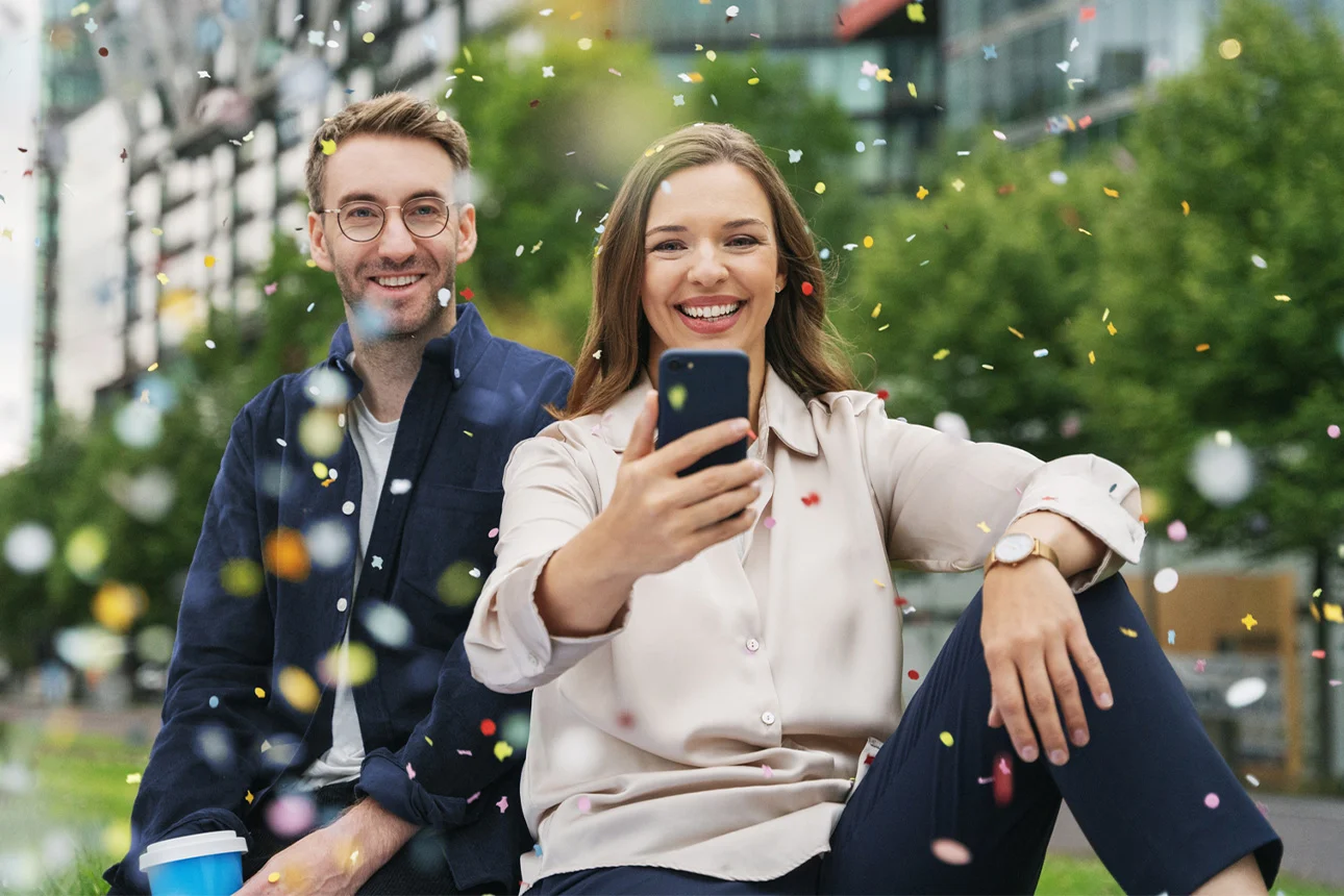 Mann und Frau mit Smartphone im Konfetti-Regen