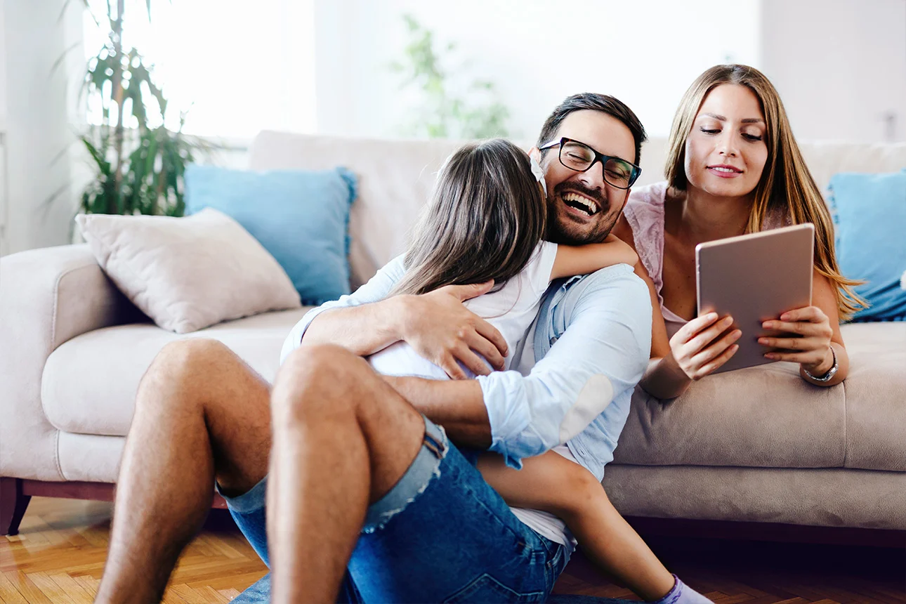 Ein Frau und ein Mann spielen mit einem Kind auf der Couch.