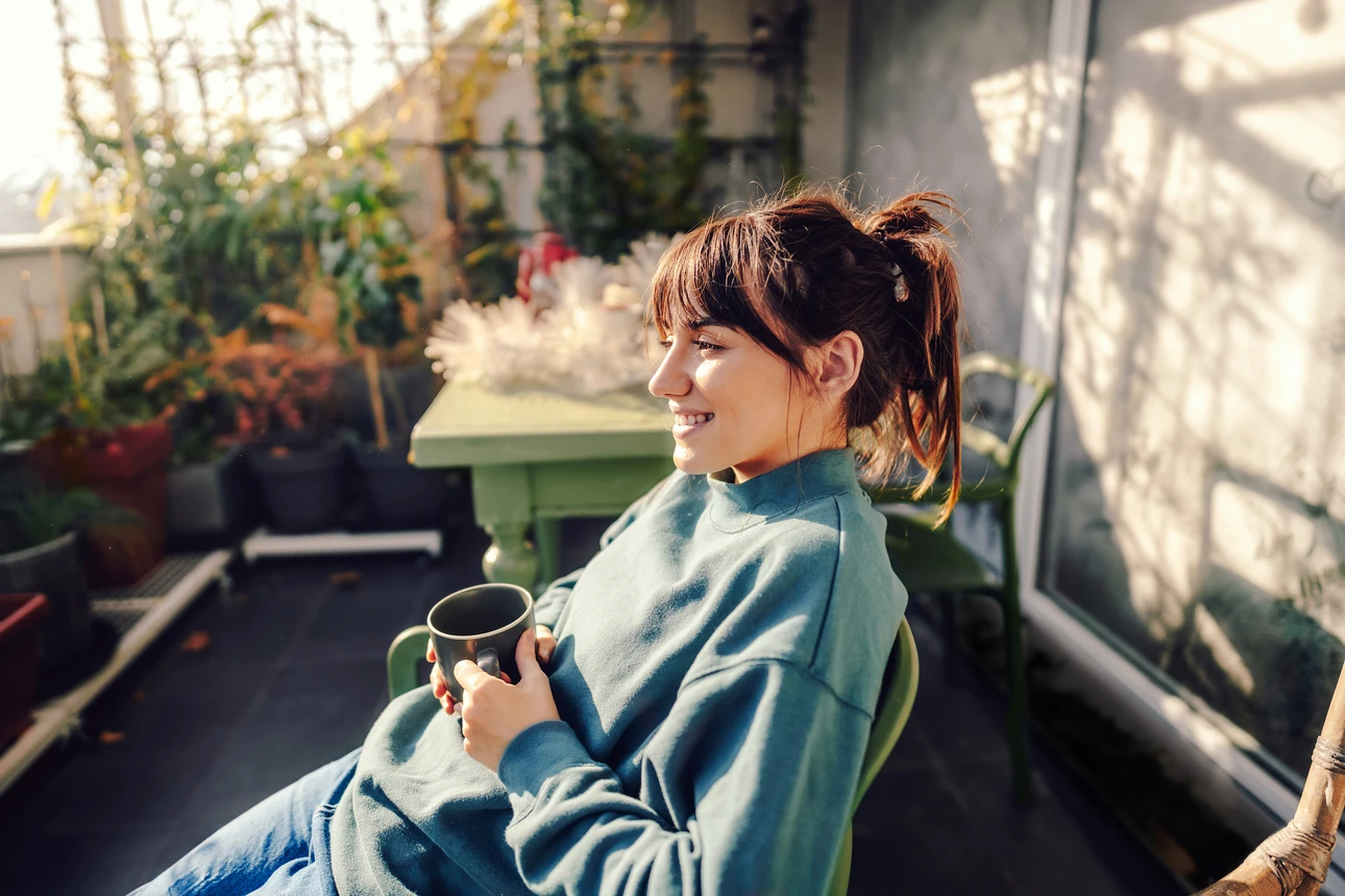 Eine Frau sitzt auf einem Balkon und trinkt Kaffee