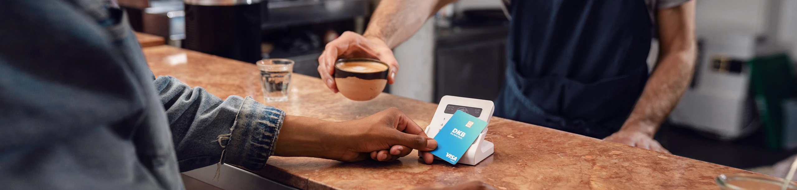 Person bezahlt mit Debitkarte am Kartenterminal im Café