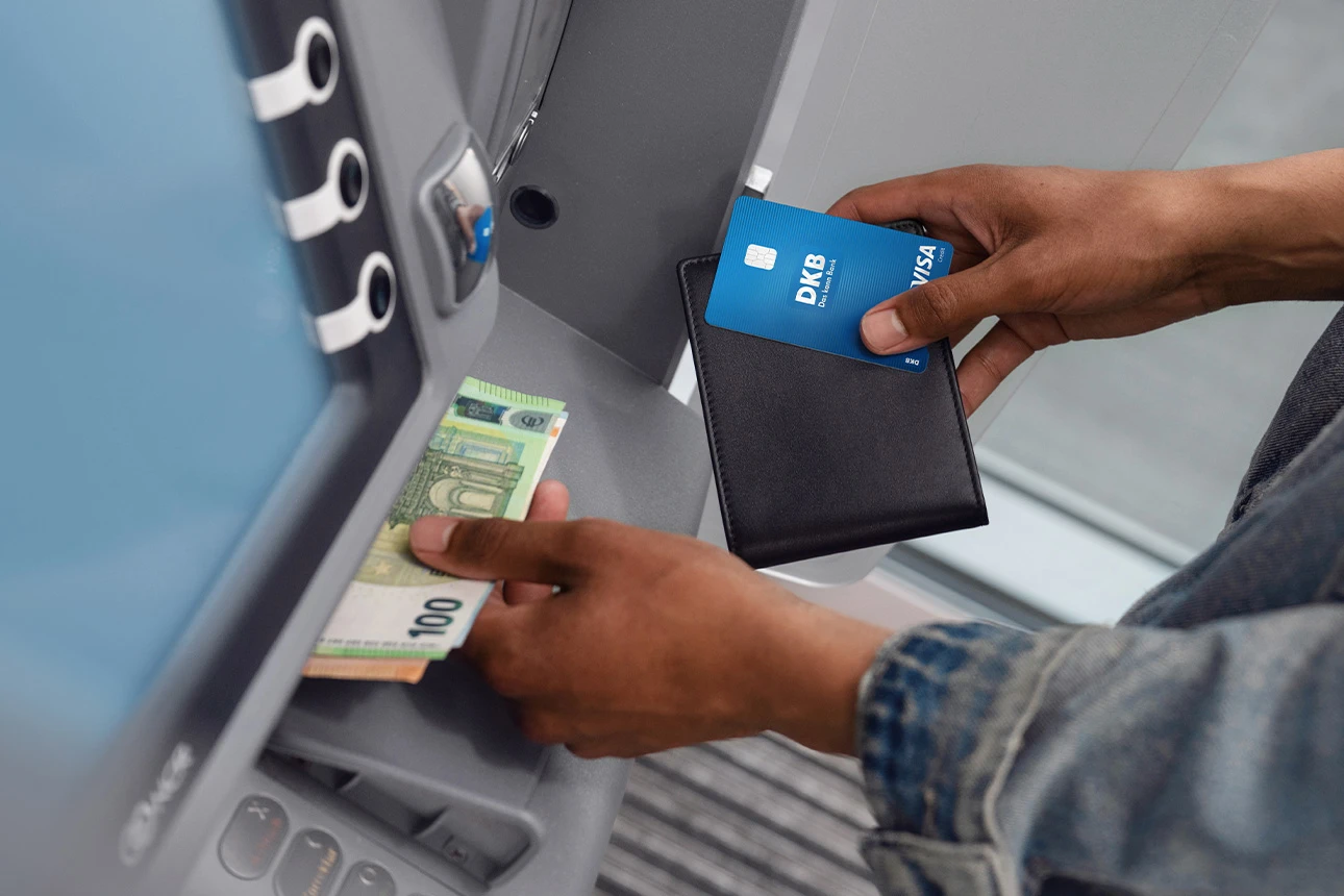 Person hebt mit Visa Debitkarte Bargeld am Geldautomaten ab
