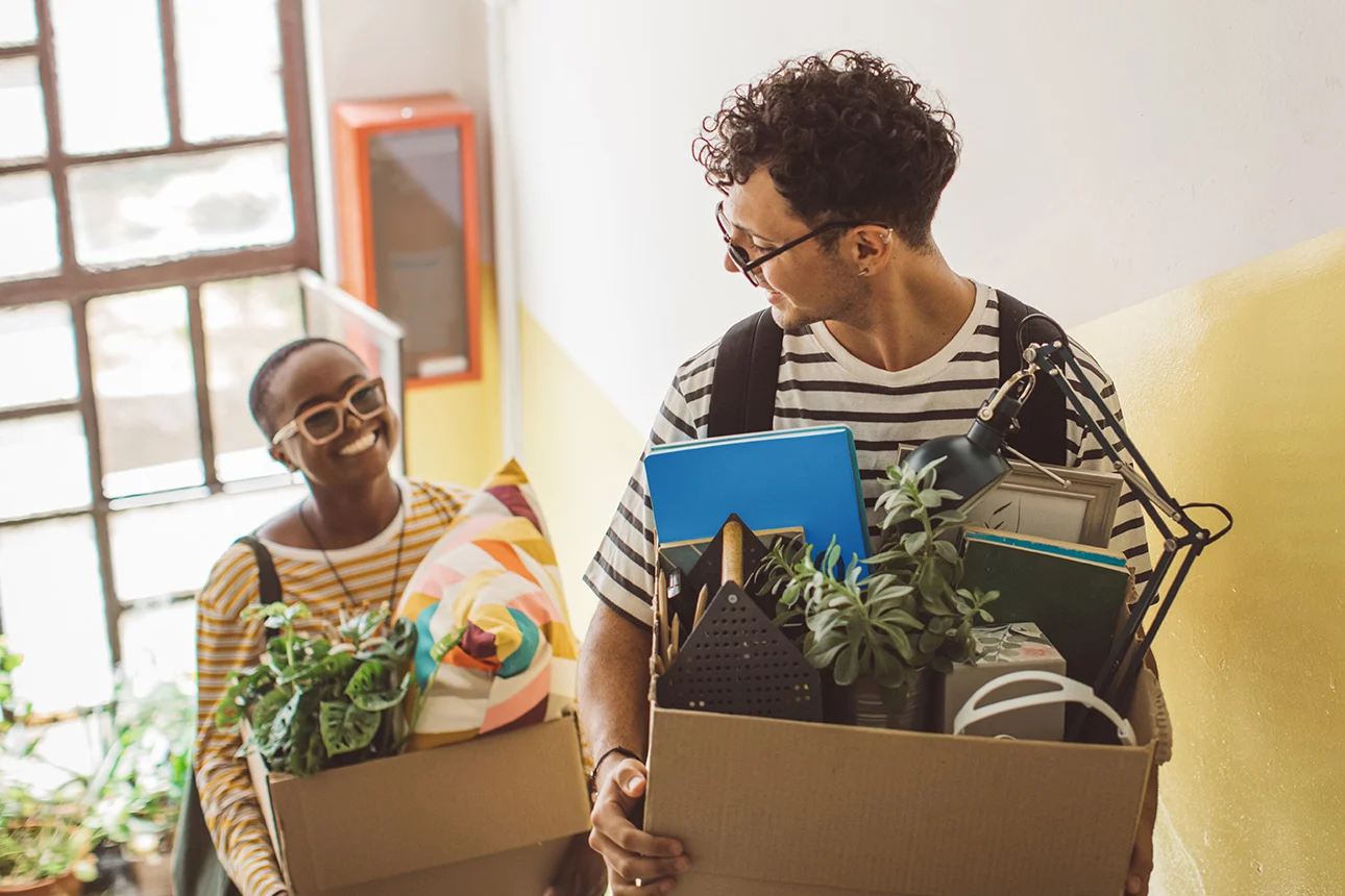 Zwei Menschen tragen gemeinsam Umzugskartons in die Wohnung