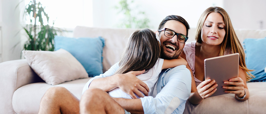 Mädchen umarmt Vater, während Mutter den Sparplan aufsetzt