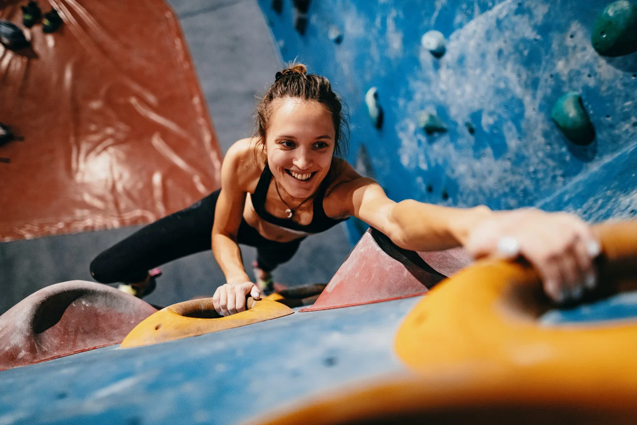 Frau klettert an einer Kletterwand