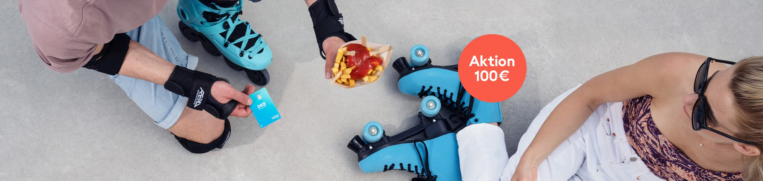 Zwei Rollschuhfahrer essen Pommes. Einer hält eine DKB Debitkarte in der Hand