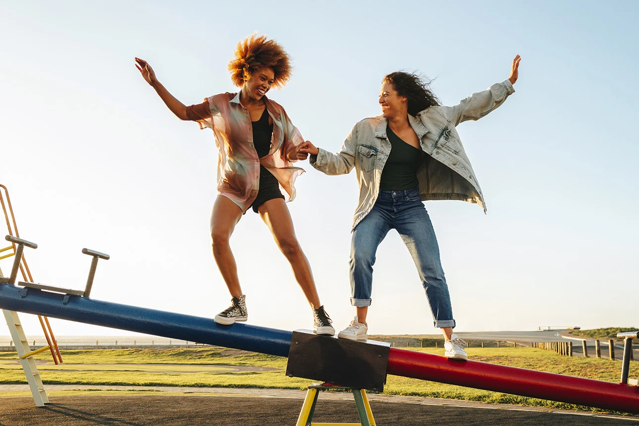 Zwei Frauen balancieren auf einer Wippe auf einem Spielplatz