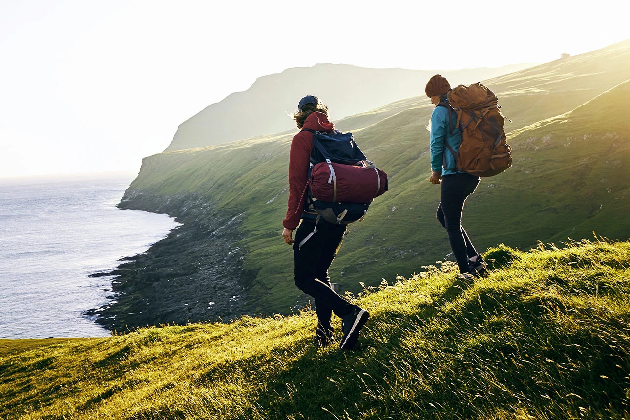 Zwei Personen wandern in einer grünen Landschaft