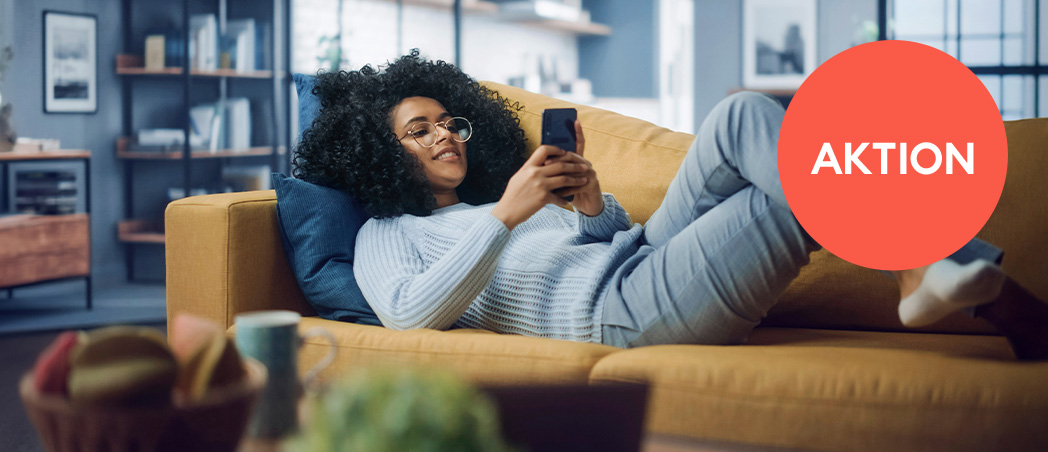 Junge Frau liegend auf Couch mit Handy in der Hand