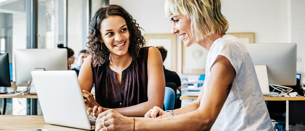 Zwei Frauen arbeiten gemeinsam am Laptop im modernen Büro