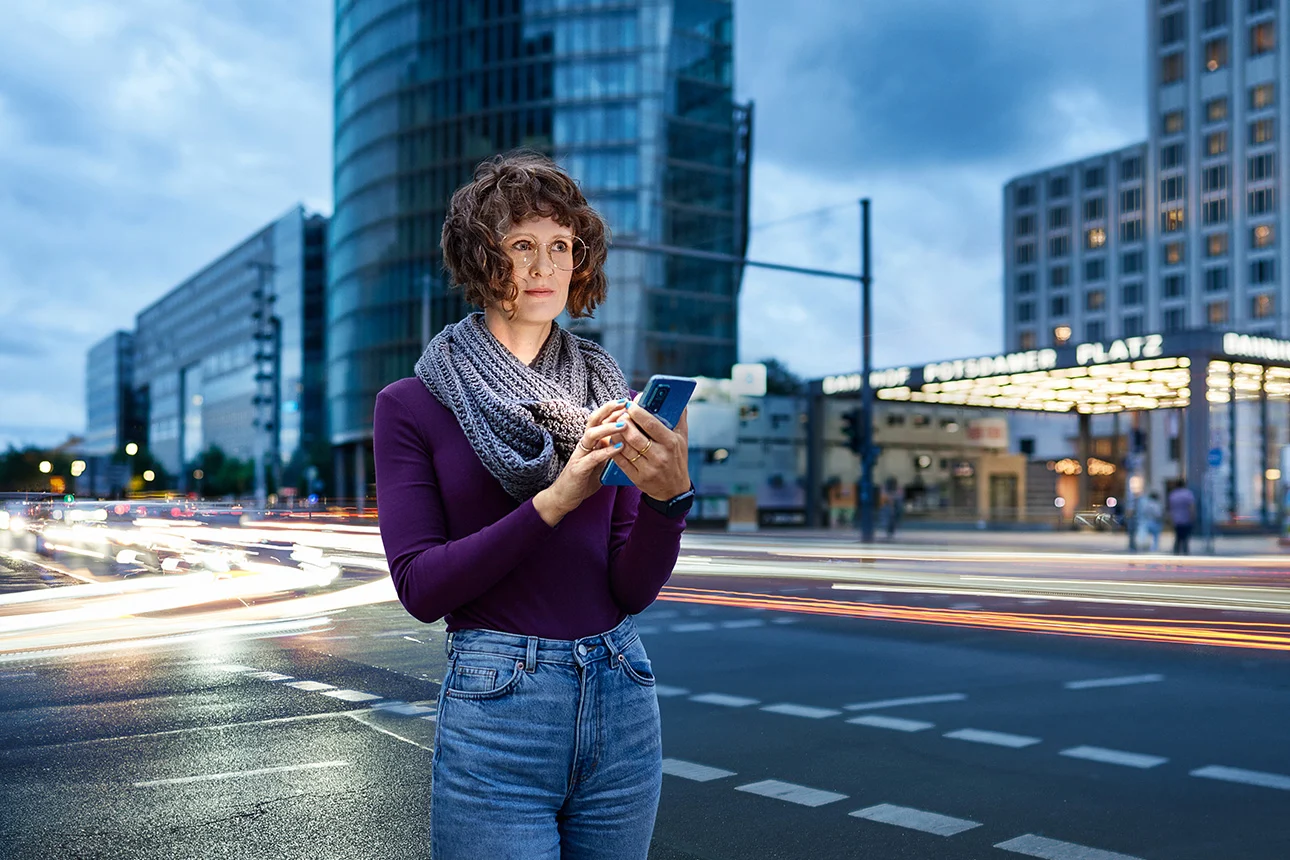 Frau steht mit Handy auf der Straße