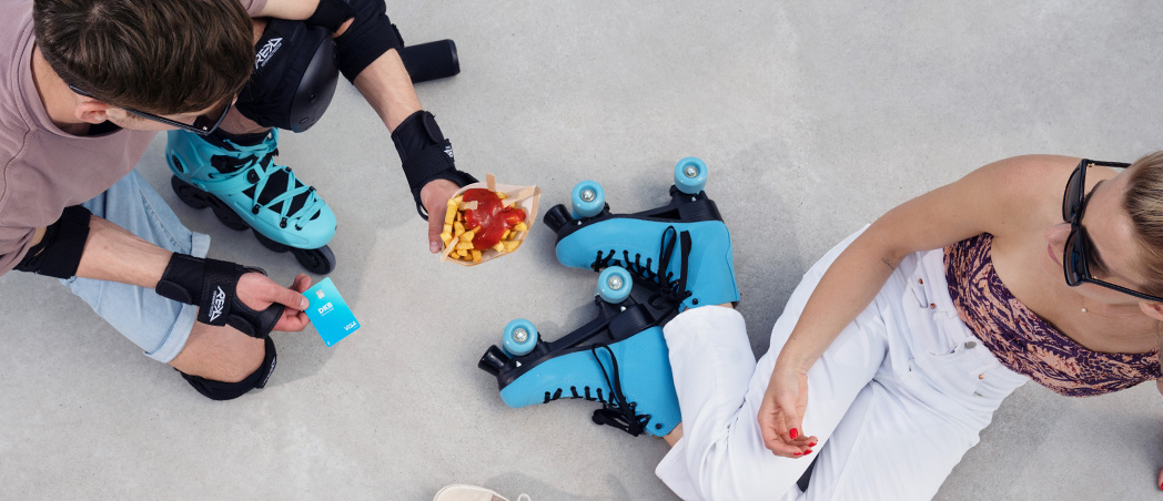 Zwei Studierende mit Rollschuhen und Visa Debitkarte