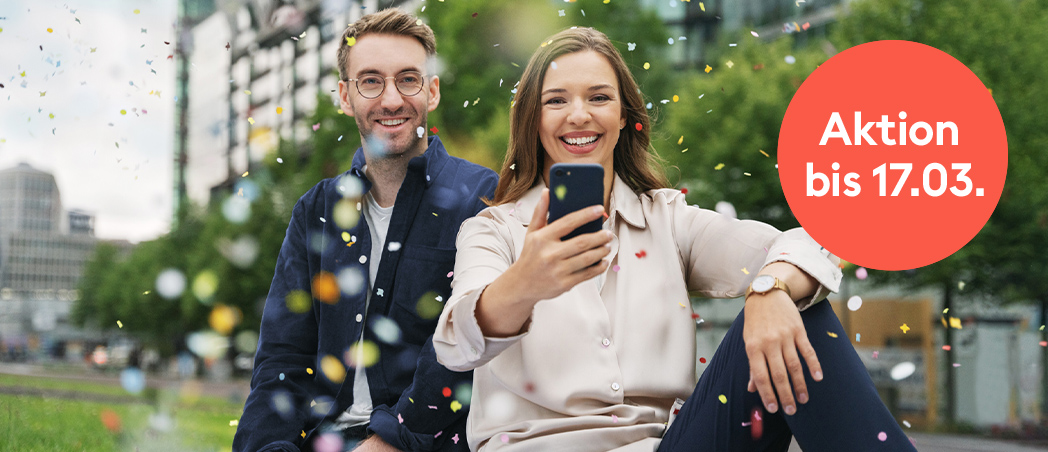 Mann und Frau mit Smartphone im Konfetti-Regen
