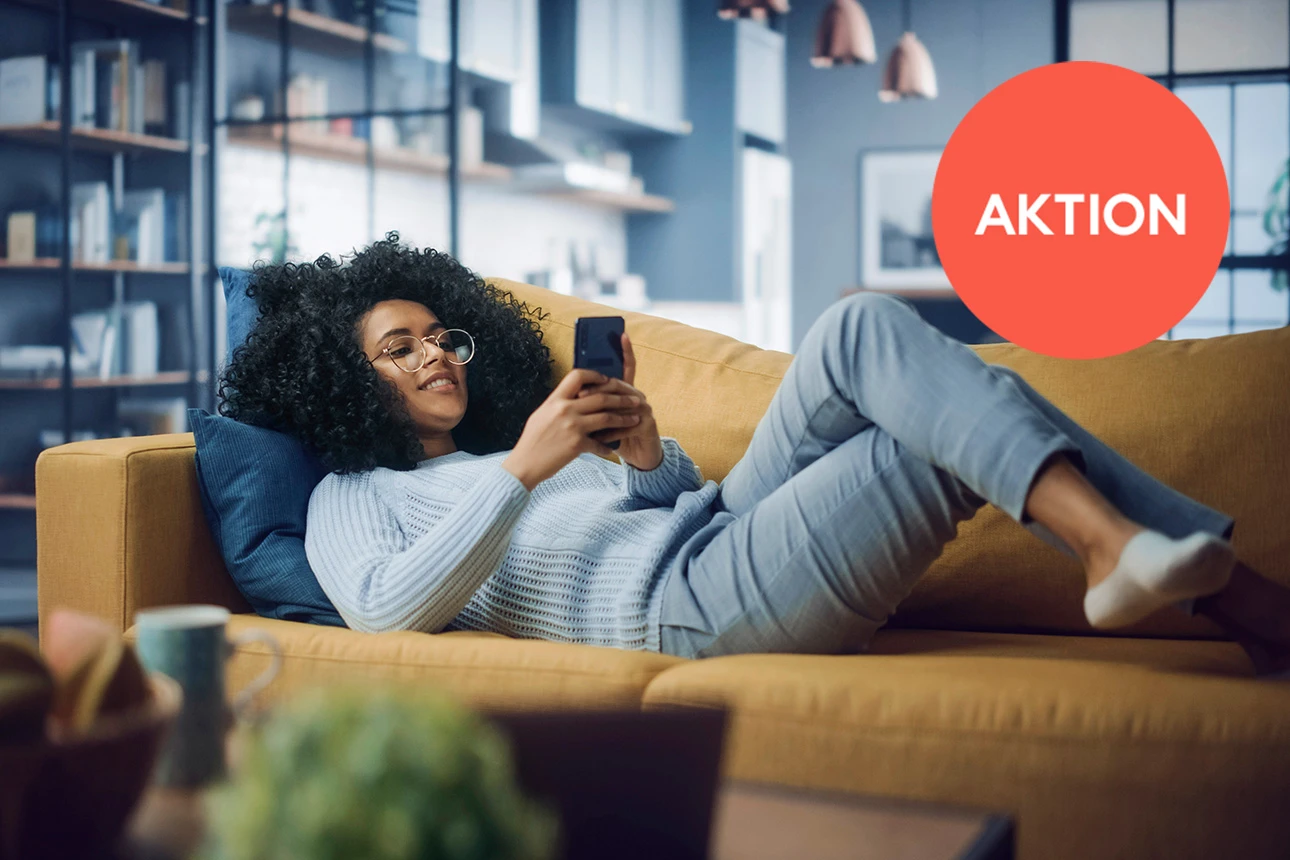 Junge Frau liegend auf Couch mit Handy in der Hand