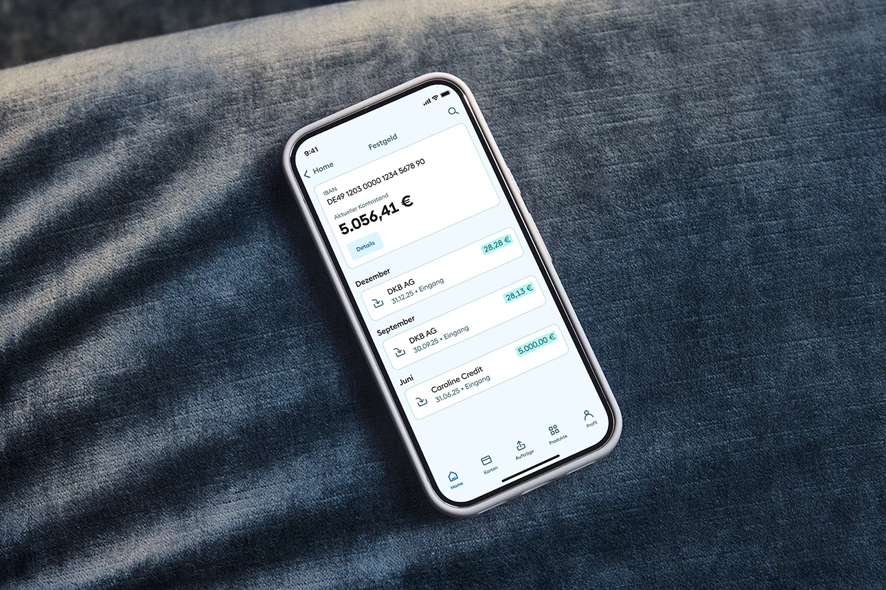 Ein Mobiltelefon mit dem Festgeld der DKB liegt auf einer Couch