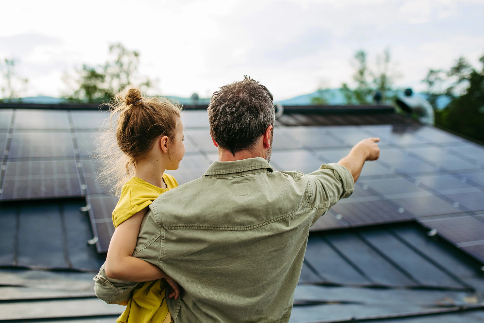 Vater und Tochter betrachten Solarmodule auf dem Hausdach