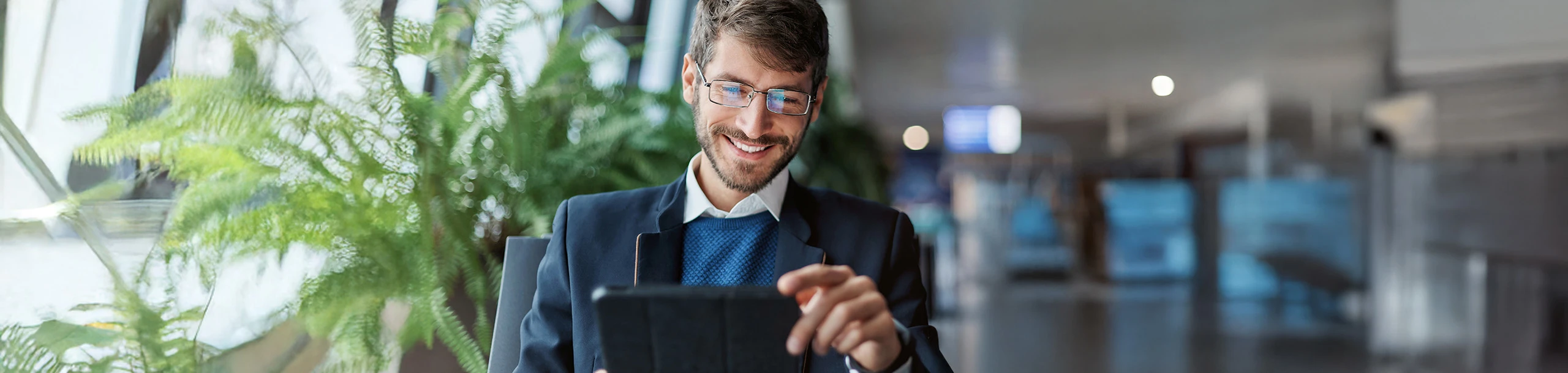 Ein Mann sitzt in einem Stuhl mit einem Tablet in der Hand