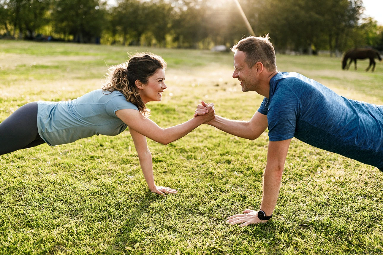 Eine Frau und ein Mann machen zusammen Sport im Park.