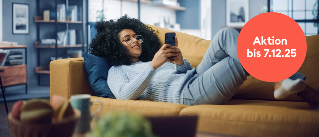 Junge Frau liegend auf Couch mit Handy in der Hand