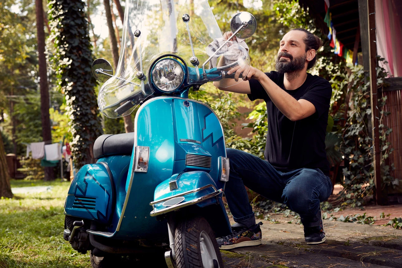 Ein Mann poliert sein blaues Moped.