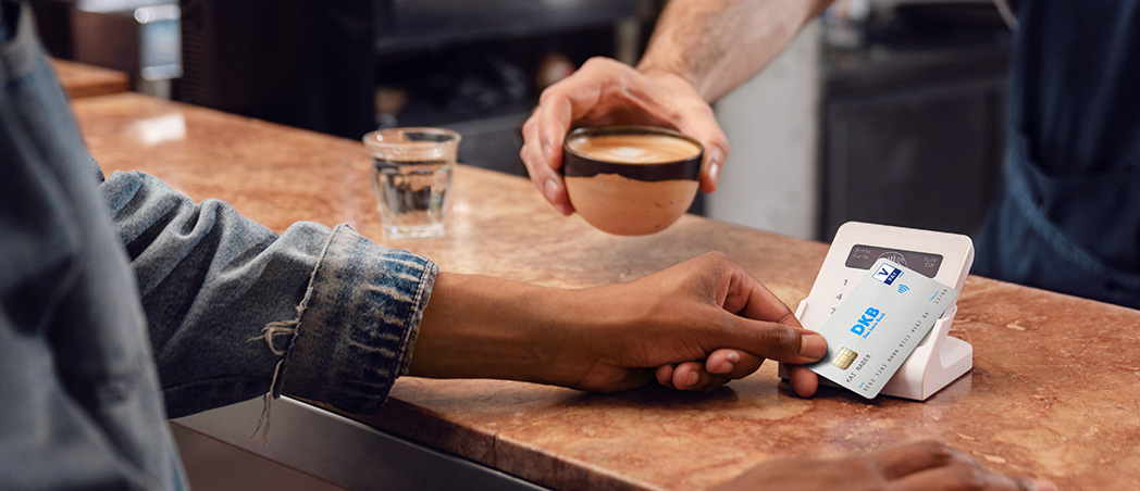 Person bezahlt mit Girokarte am Kartenterminal im Café