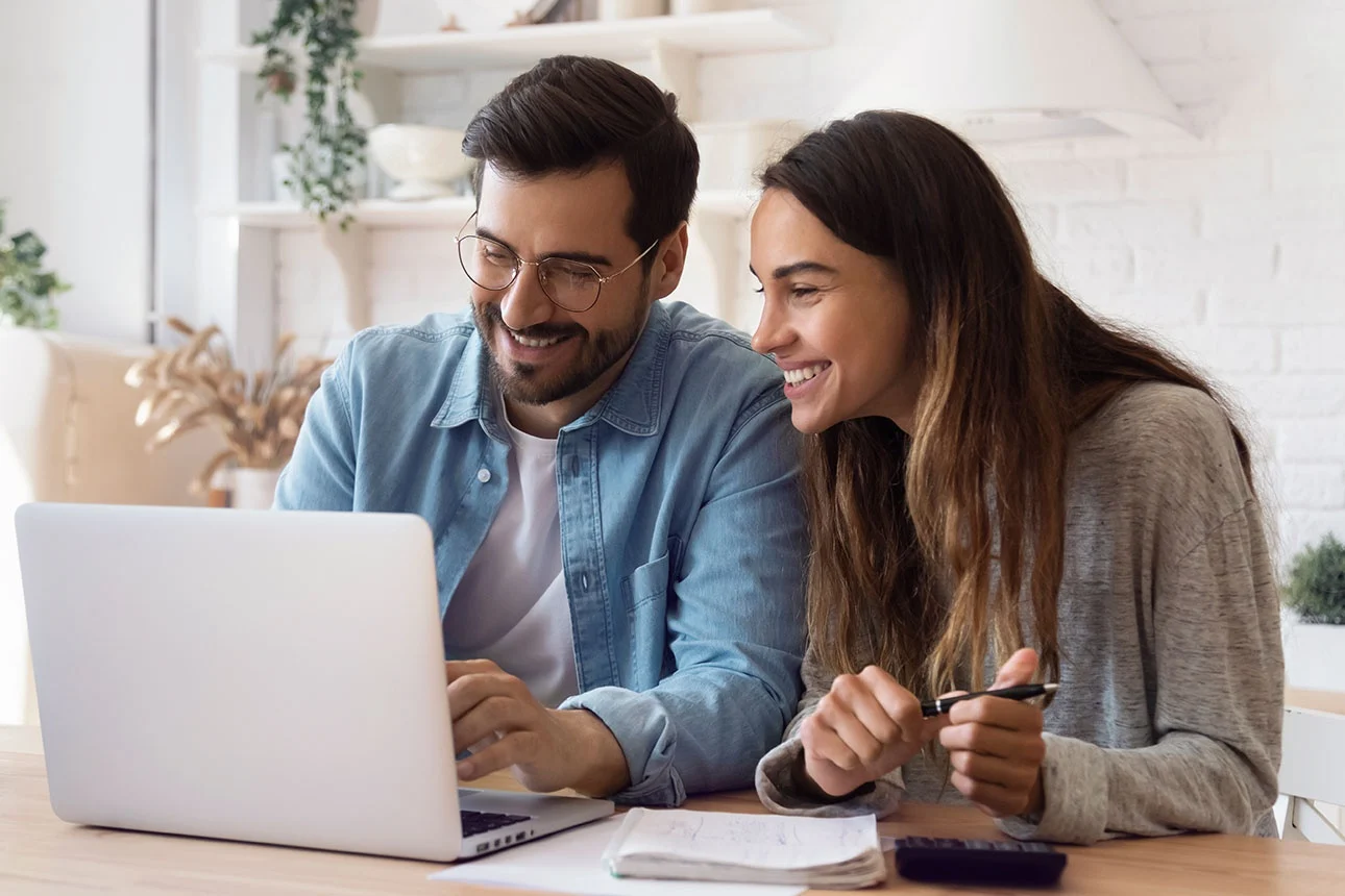 Mann und Frau sitzen am Tisch vor Laptop