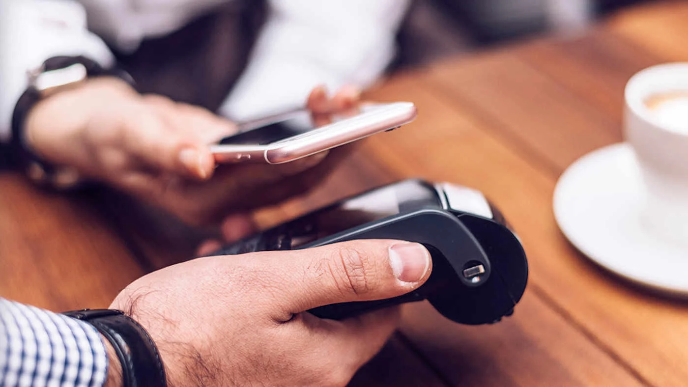 Mobile Payment: Ein Smartphone bei einer kontaktlosen Zahlung an einem Bezahlterminal im Cafe.